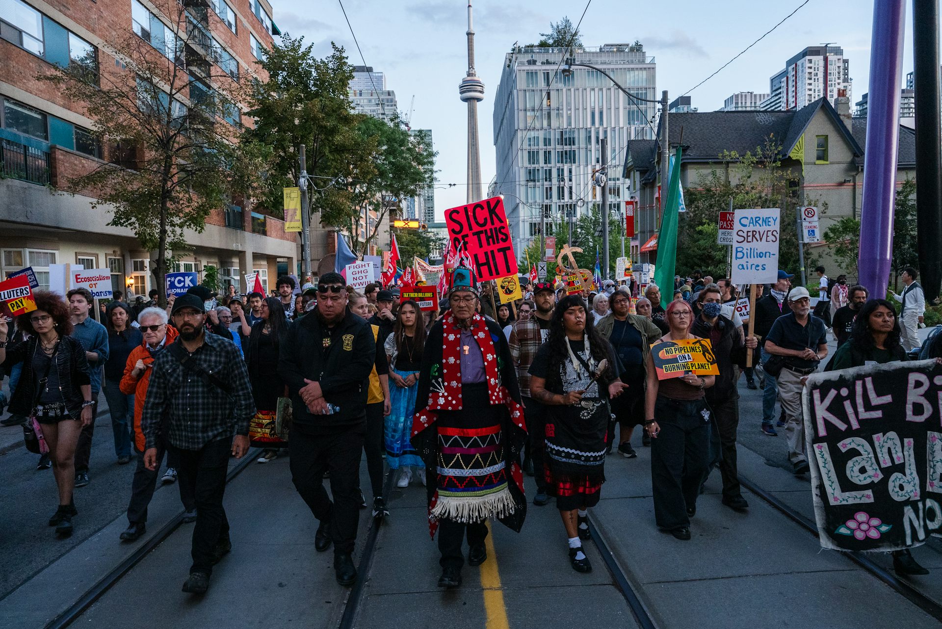 A large group of people walk down a city street carrying protest signs