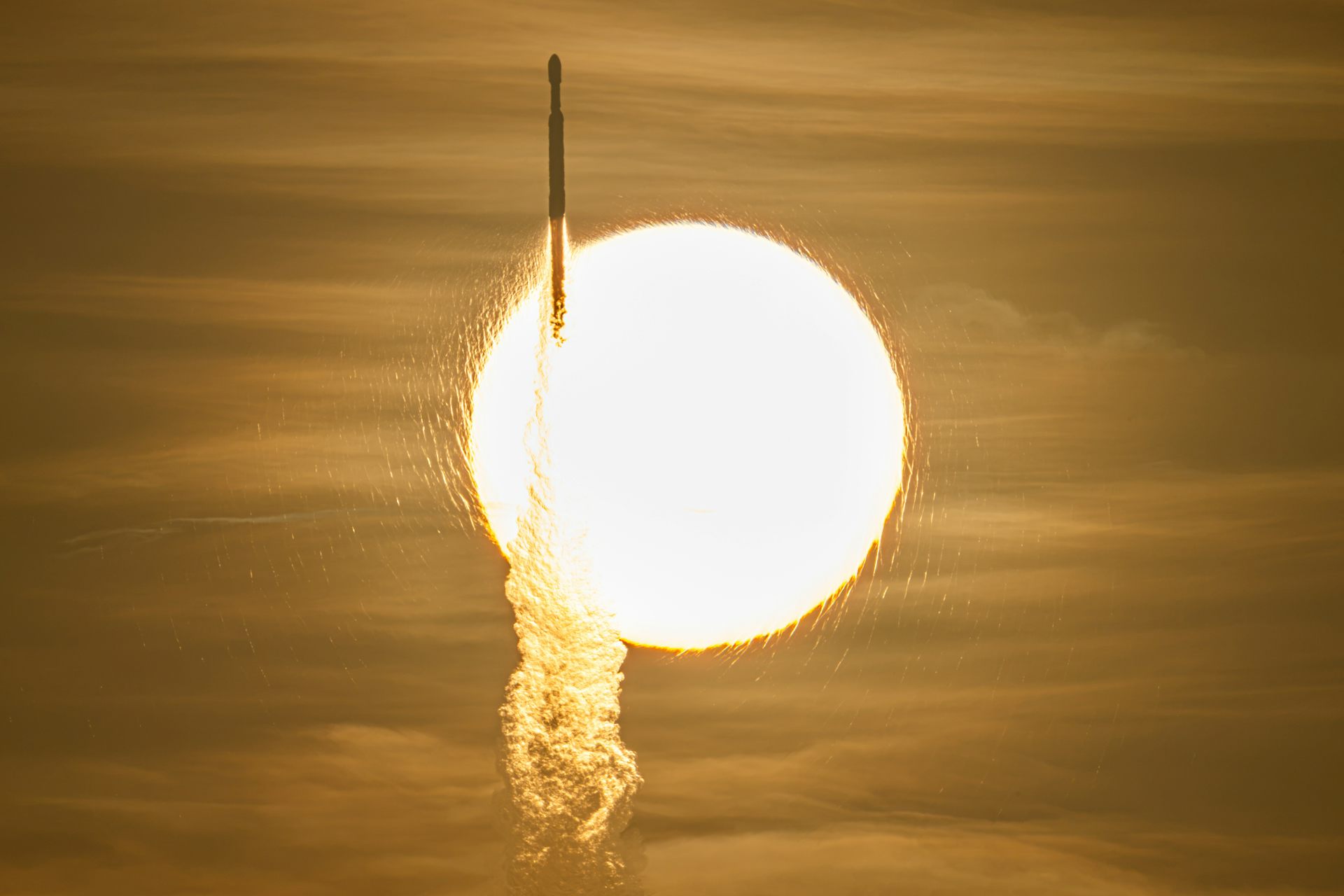 A large glowing orb with a golden sky behind and a rocket travelling upwards in front of it