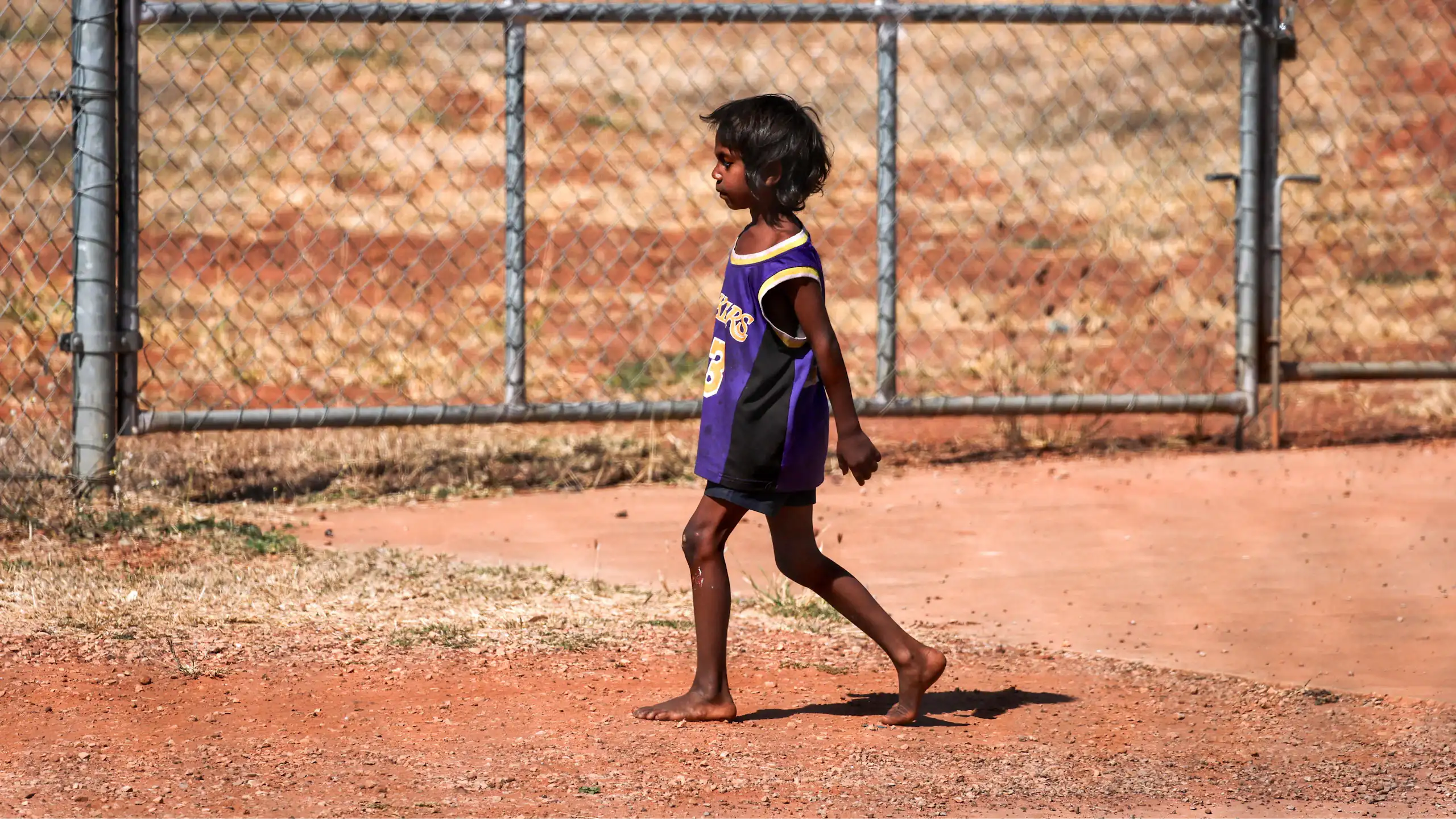 A small Indigenous boy walking alone in the outback