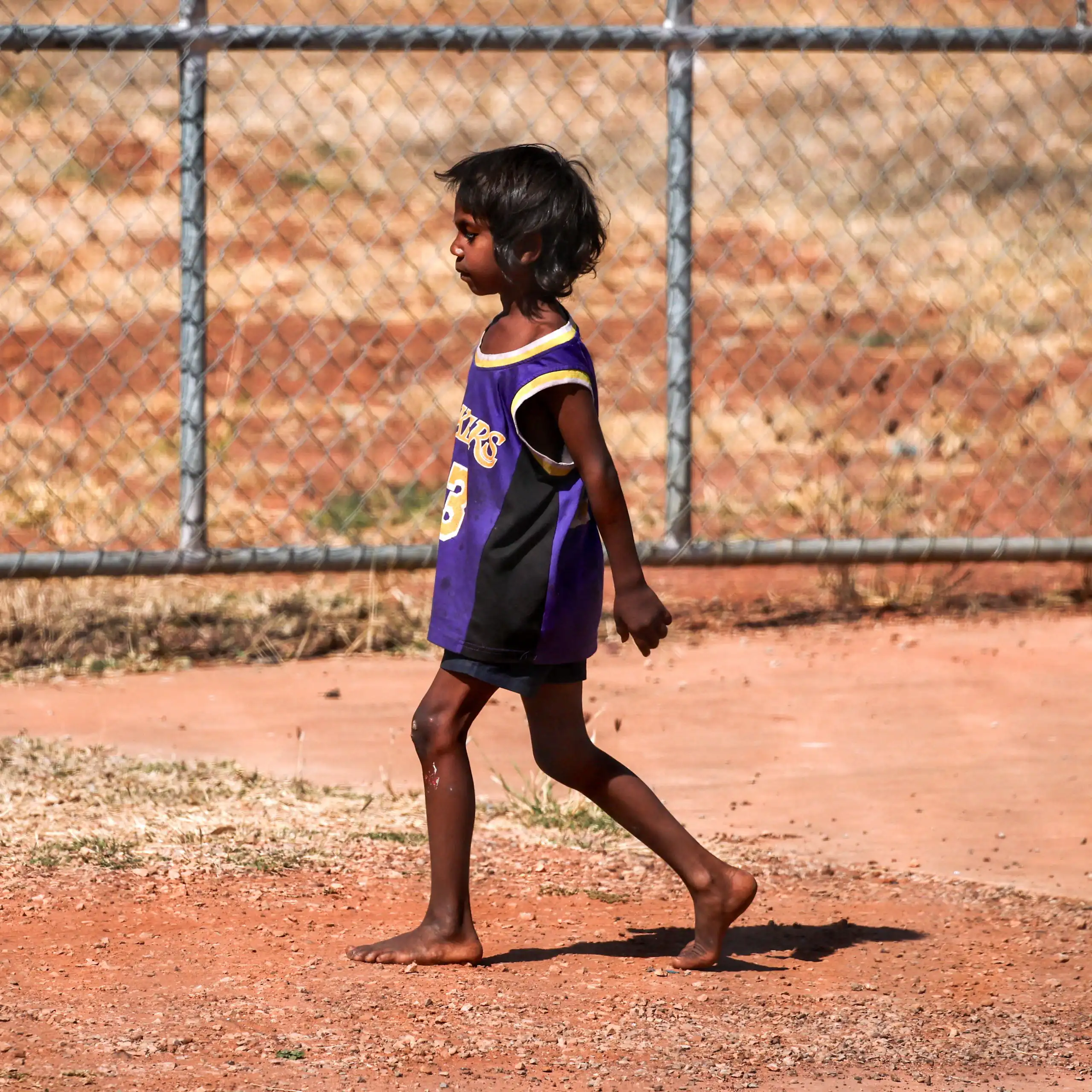 A small Indigenous boy walking alone in the outback