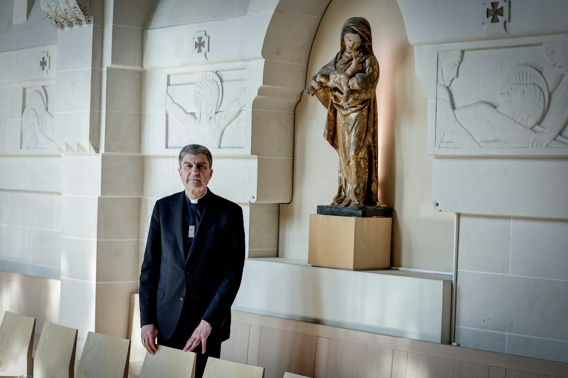 L’évêque pose devant une statue de la Vierge Marie.