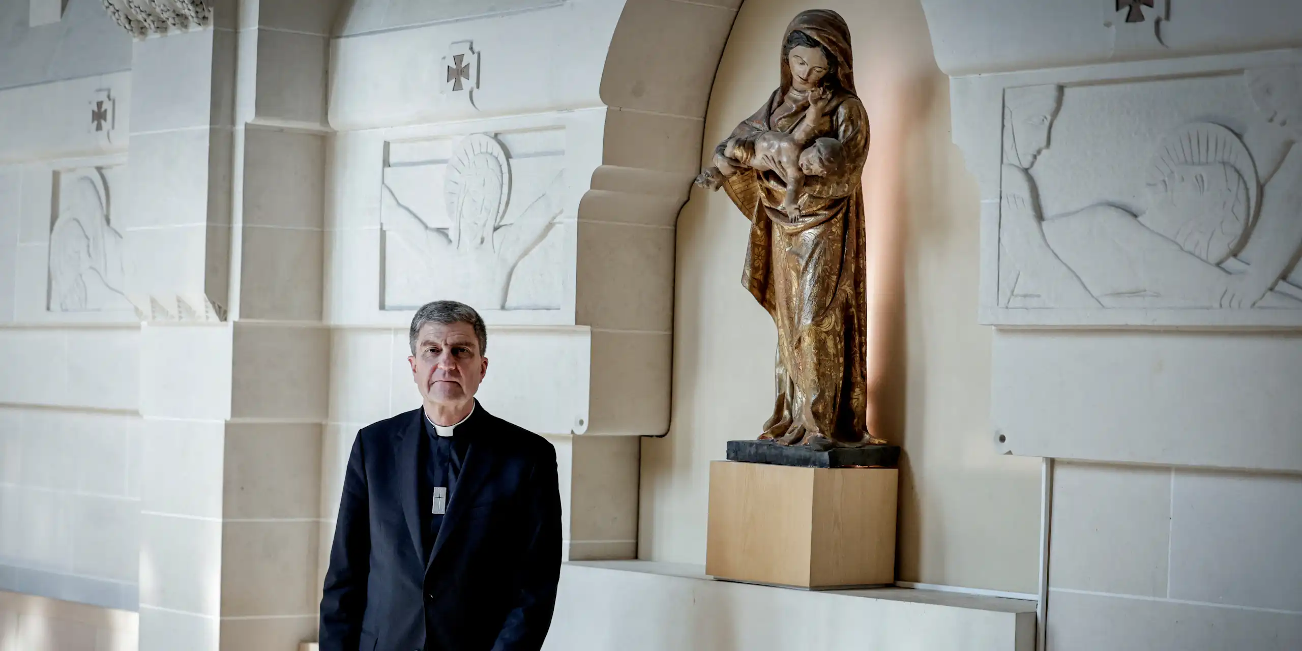 L’évêque pose devant une statue de la Vierge Marie.