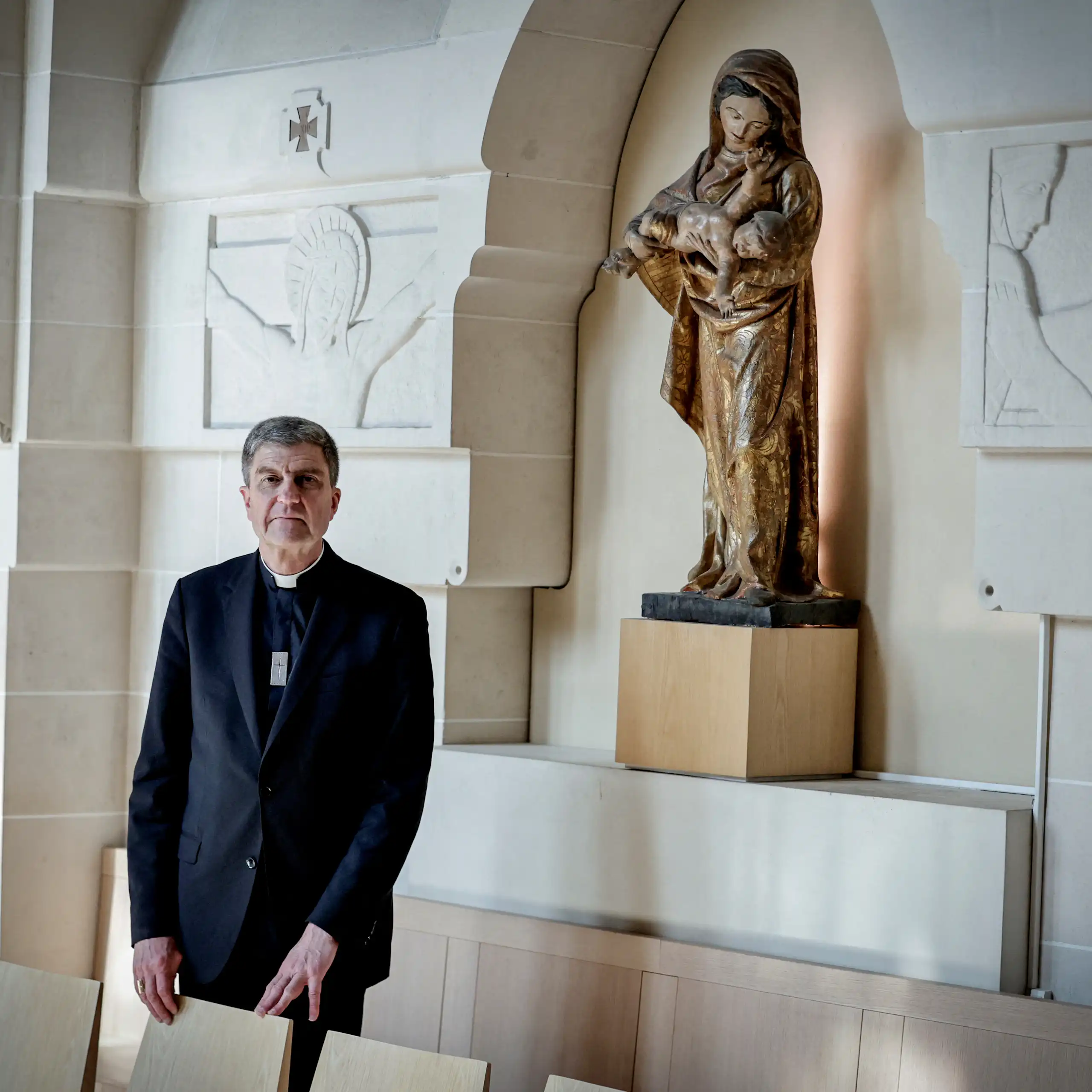 L’évêque pose devant une statue de la Vierge Marie.