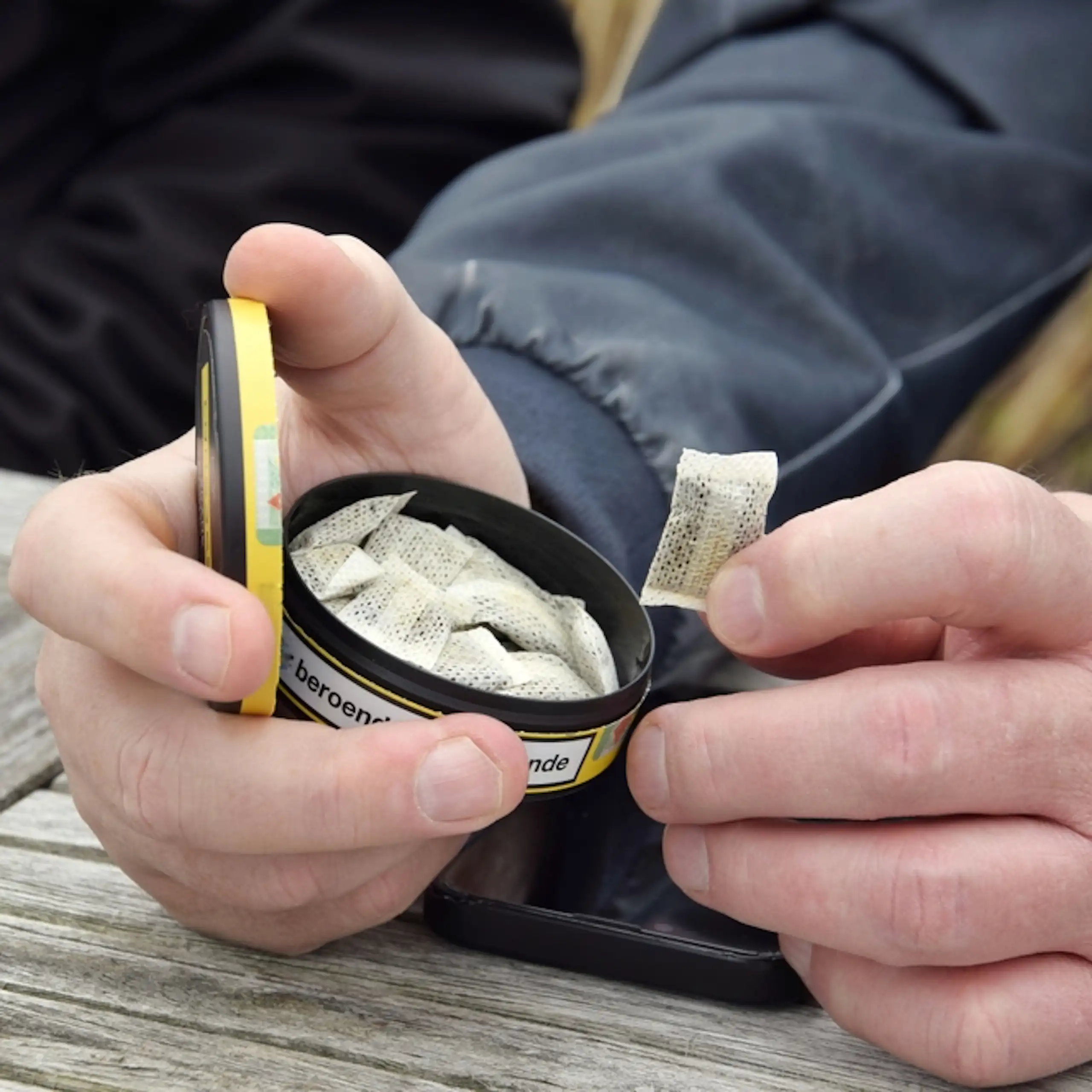 Une boîte de sachets de nicotine tenue dans la main d’un homme.