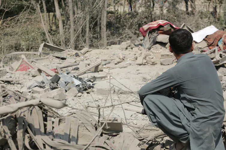 A man looks across rubble.