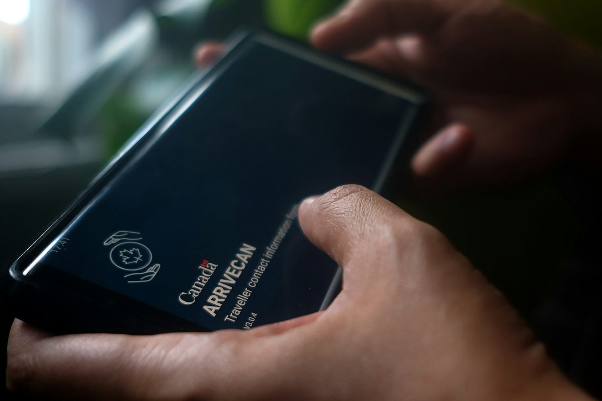 Une main tient un téléphone où s’affiche l’application ArriveCAN