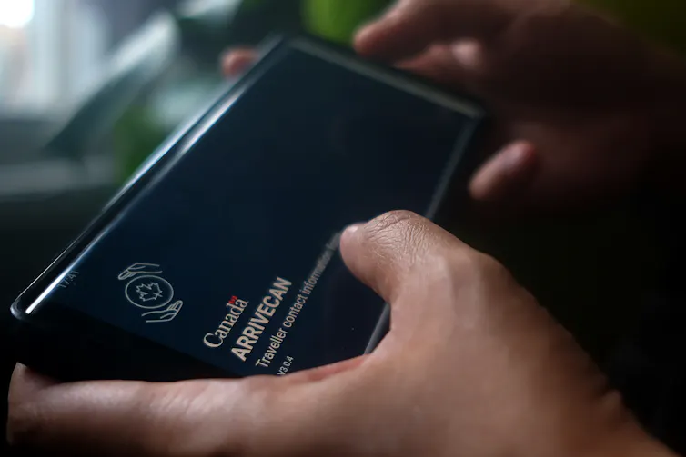 Une main tient un téléphone où s’affiche l’application ArriveCAN