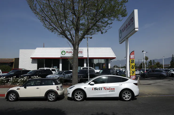 Electric cars sit on a street and in a parking lot.