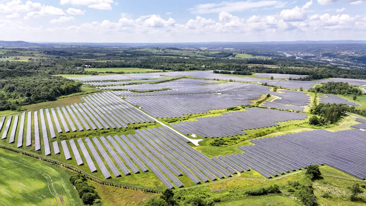 An aerial view shows a large area covered by solar panels.