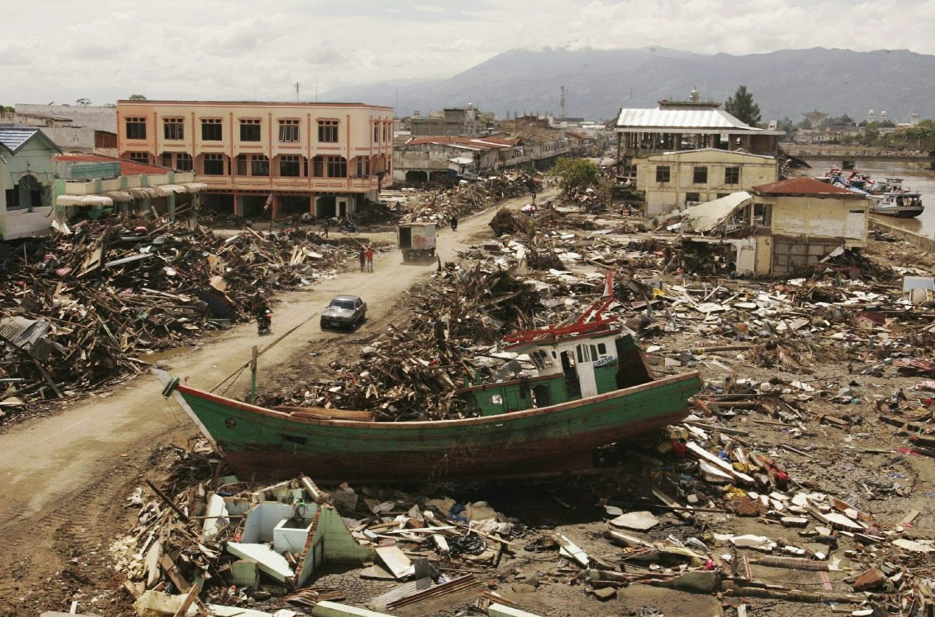 A boat lies on rubble and debris.