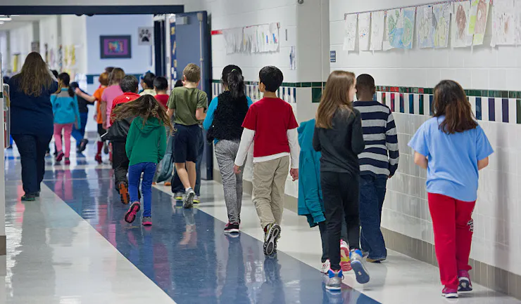 A line of students walking through a school hallway.