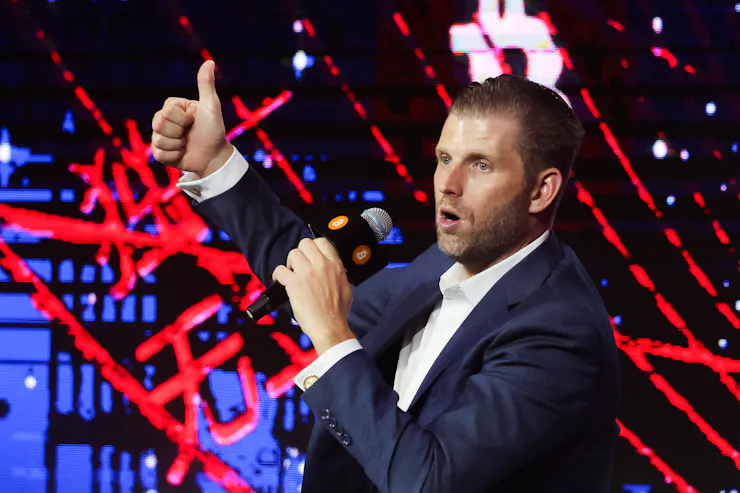 President Donald Trump's son Eric gestures to the crowd, standing against neon lights, as he speaks at the Bitcoin Asia 2025 conference in Hong Kong.
