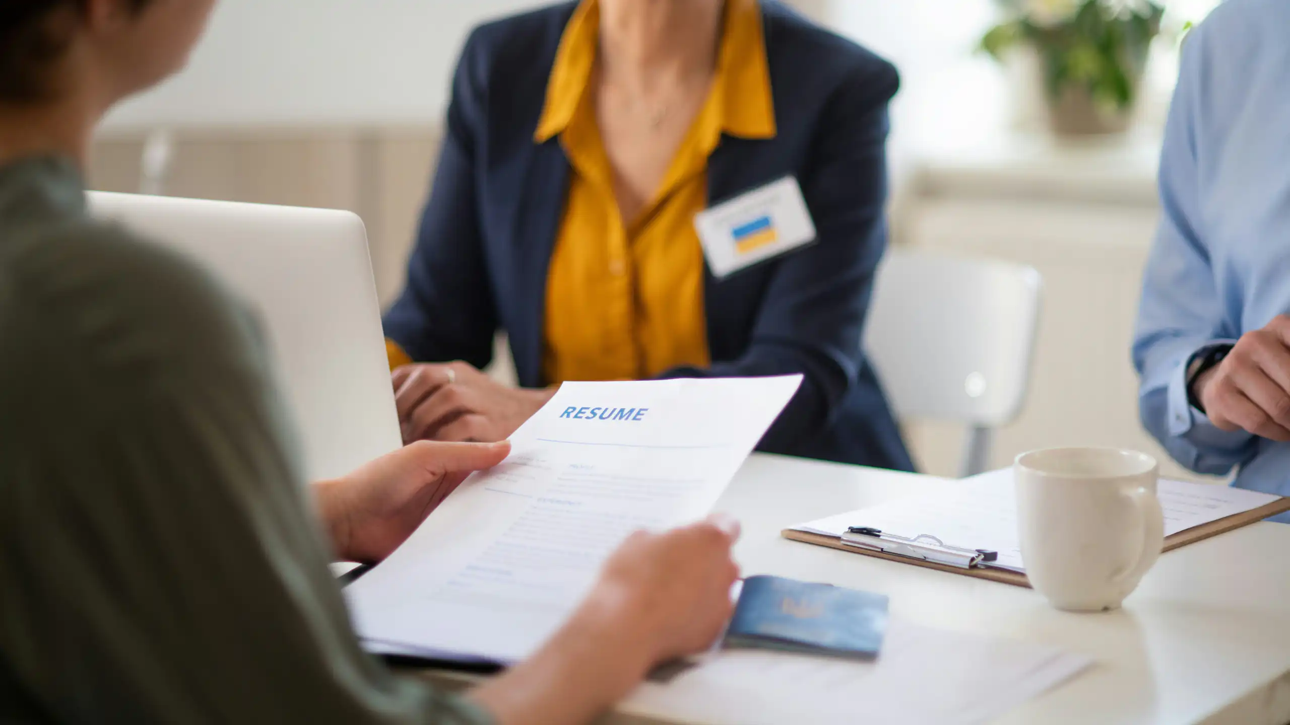 A person holding a resume, sitting in front of two people