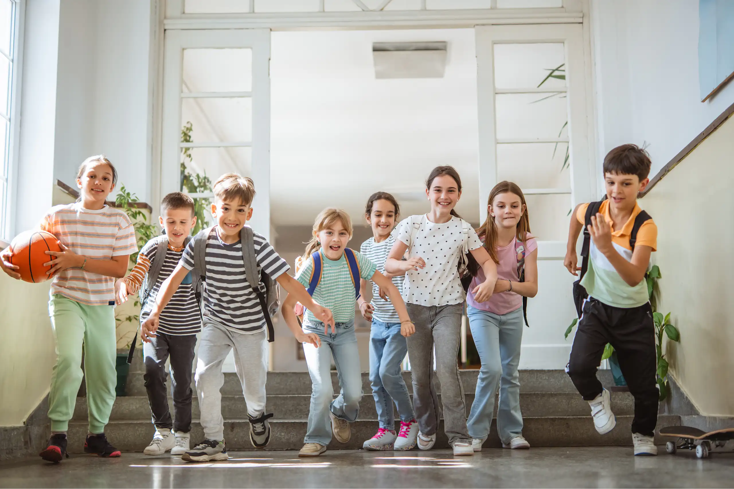 Des enfants souriants courent dans le couloir d'une école.