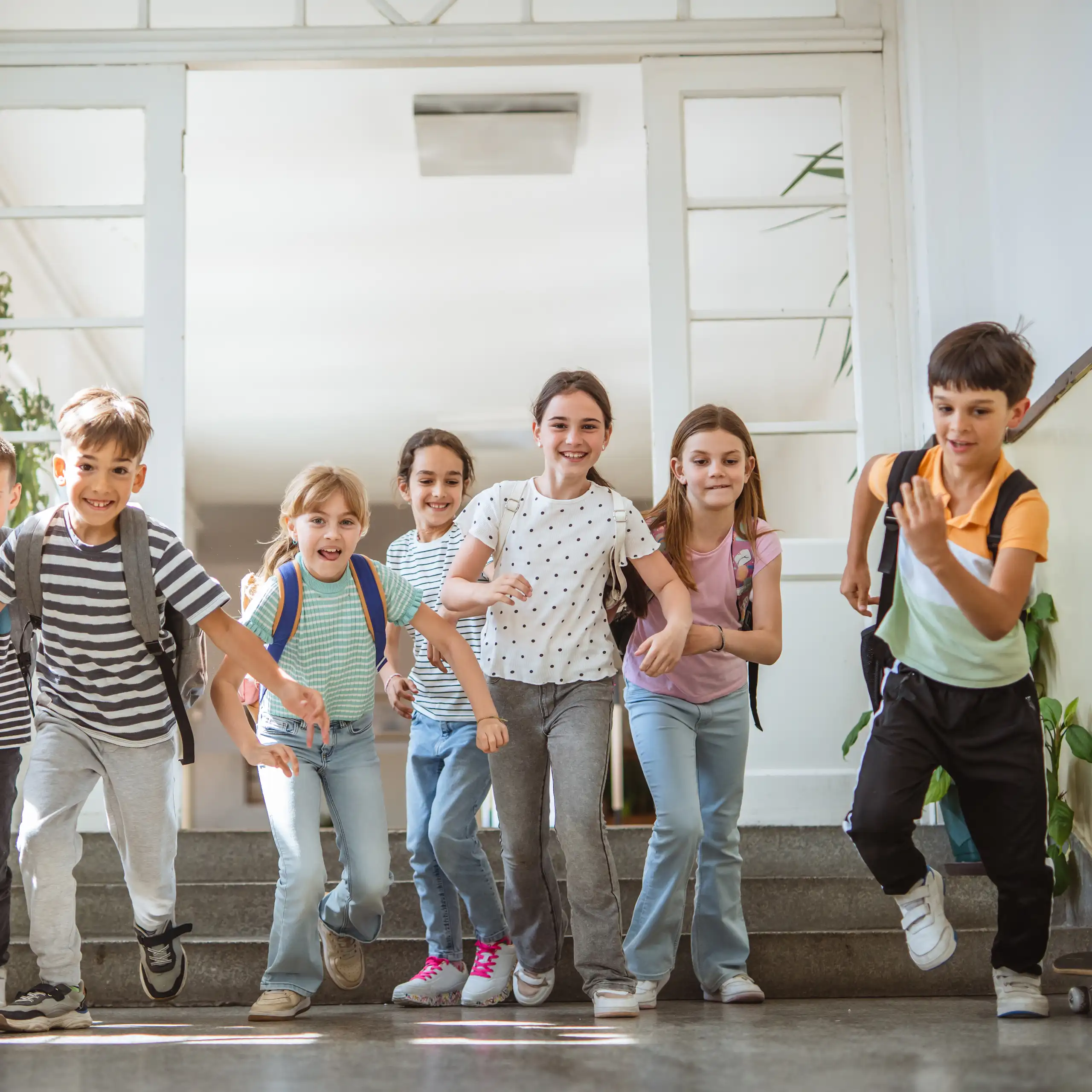Des enfants souriants courent dans le couloir d'une école.