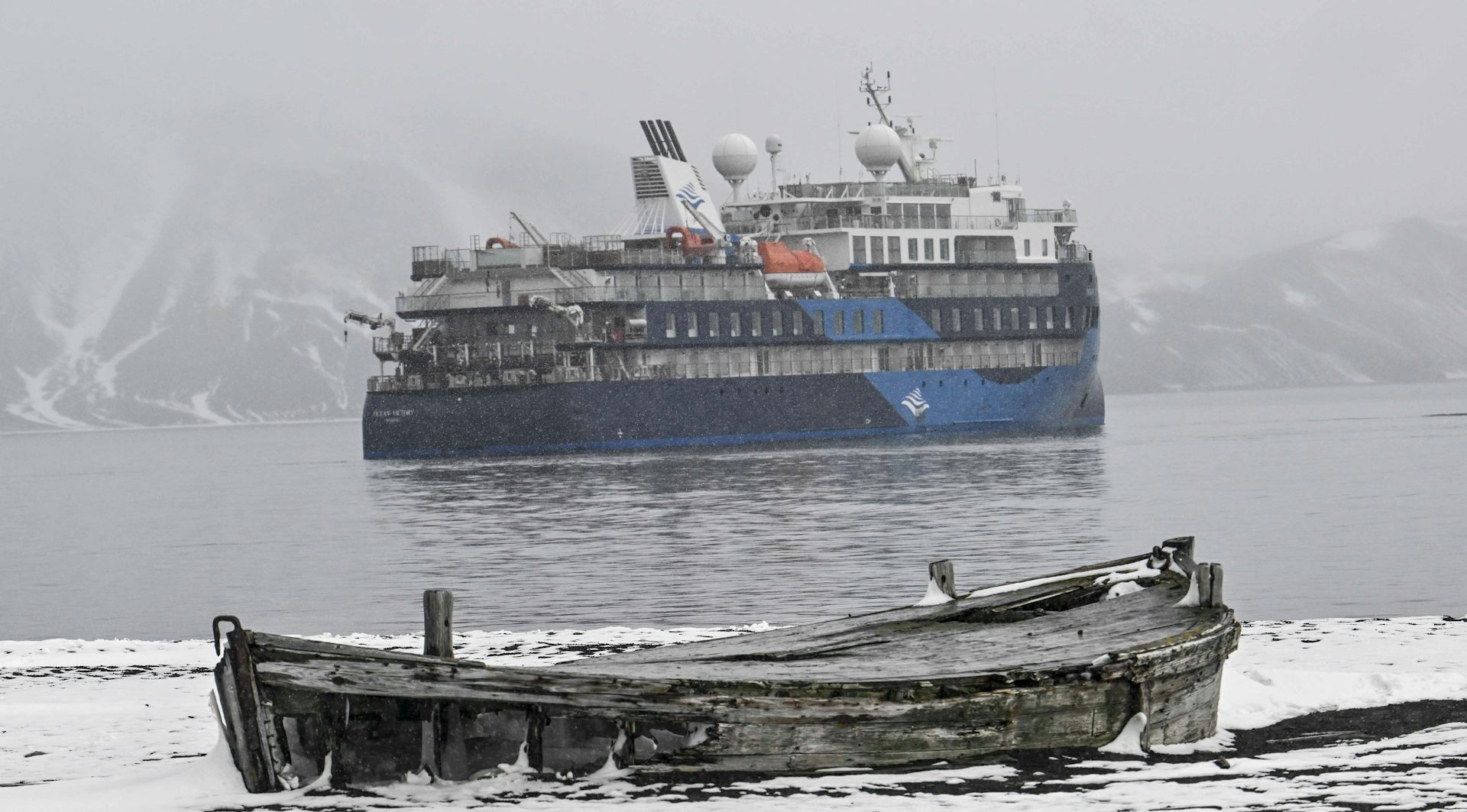 L’« Ocean Victory  » au second plan. Au premier plan, un vieux bateau en bois abandonné sur la banquise.