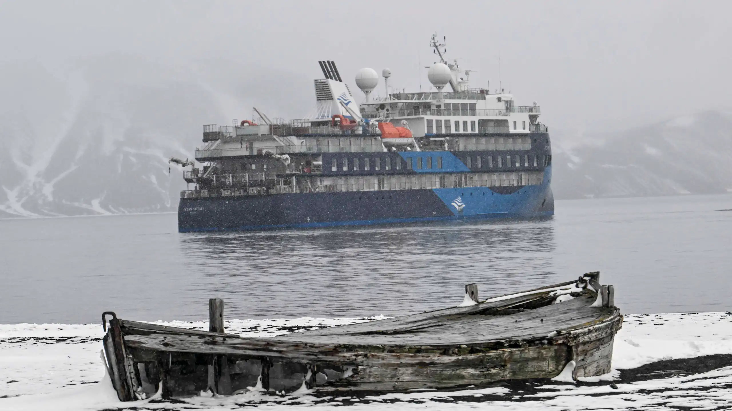L’« Ocean Victory » au second plan. Au premier plan, un vieux bateau en bois abandonné sur la banquise.