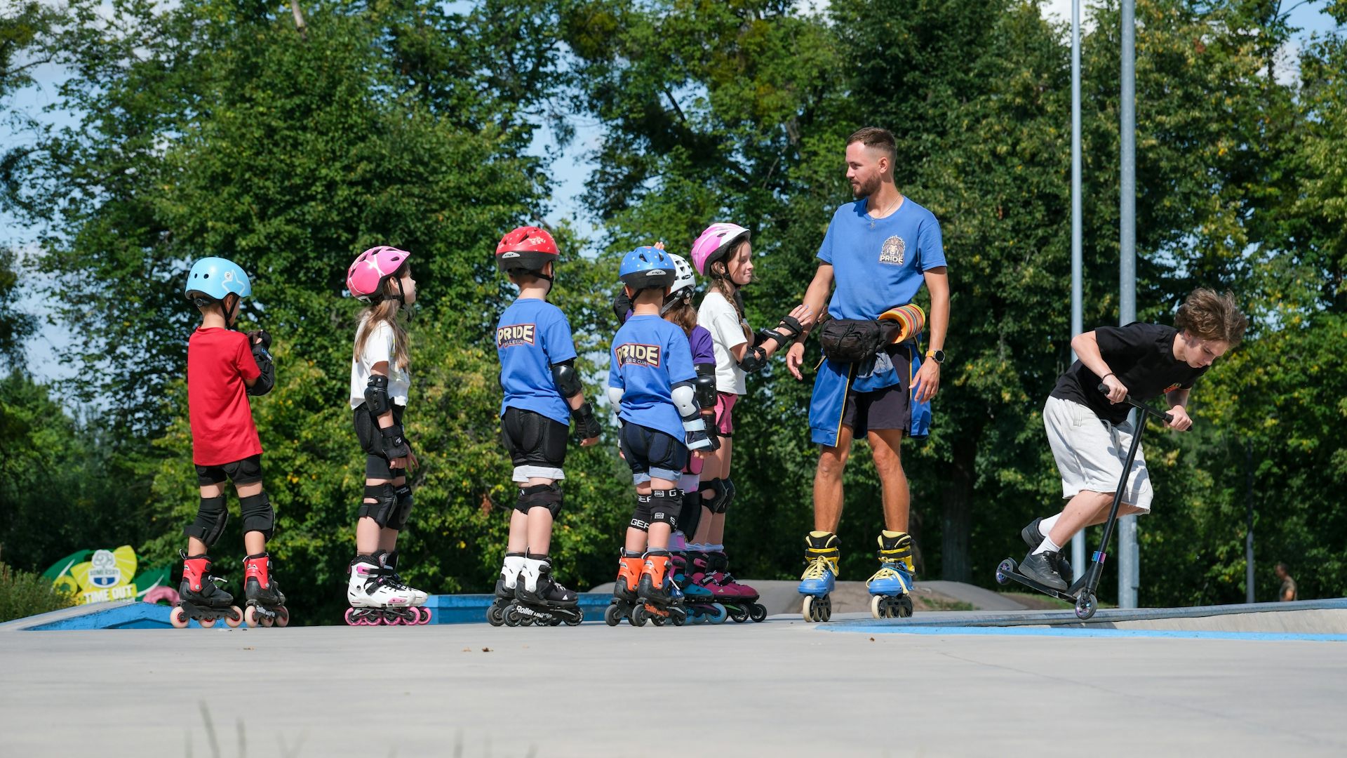 Un grup de xiquets i xiquetes amb patins practiquen a una pista amb un monitor.