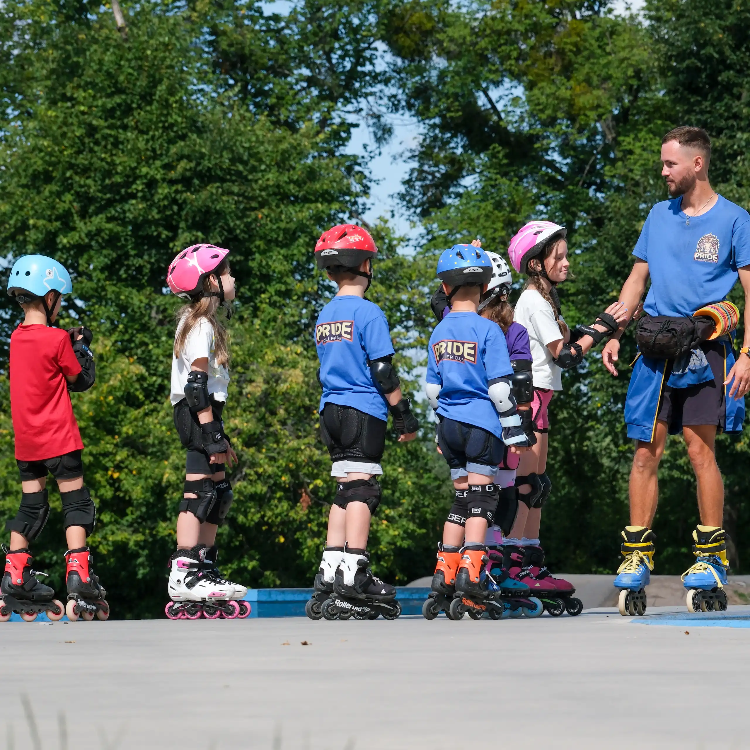 Un grup de xiquets i xiquetes amb patins practiquen a una pista amb un monitor.
