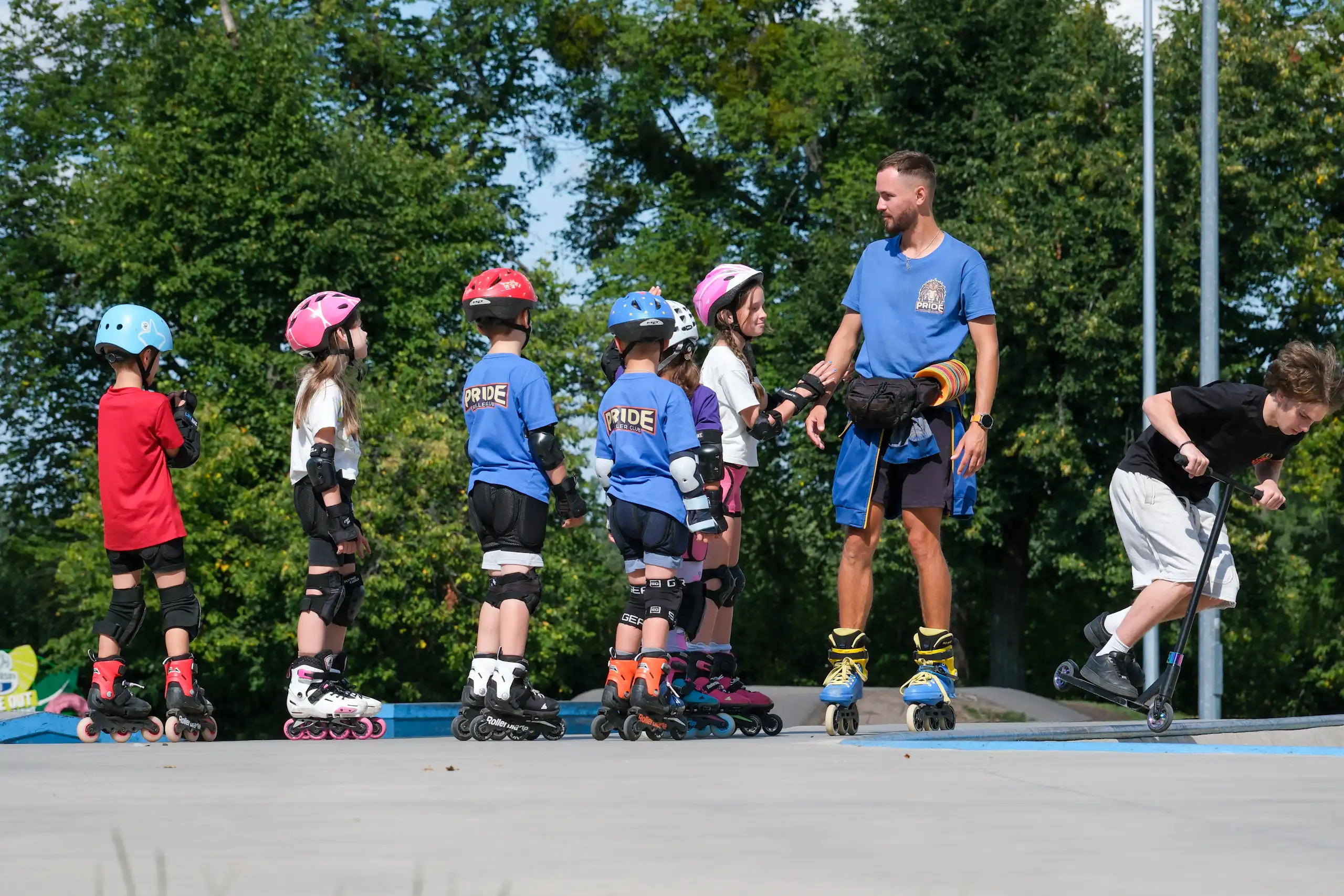 Un grup de xiquets i xiquetes amb patins practiquen a una pista amb un monitor.