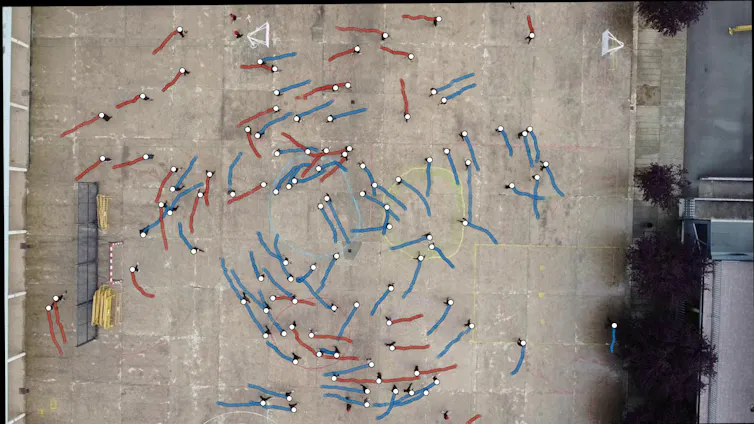 A bird's-eye view of a school playground, with coloured dots representing people moving.