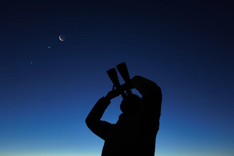 Person holding telescope up to night sky