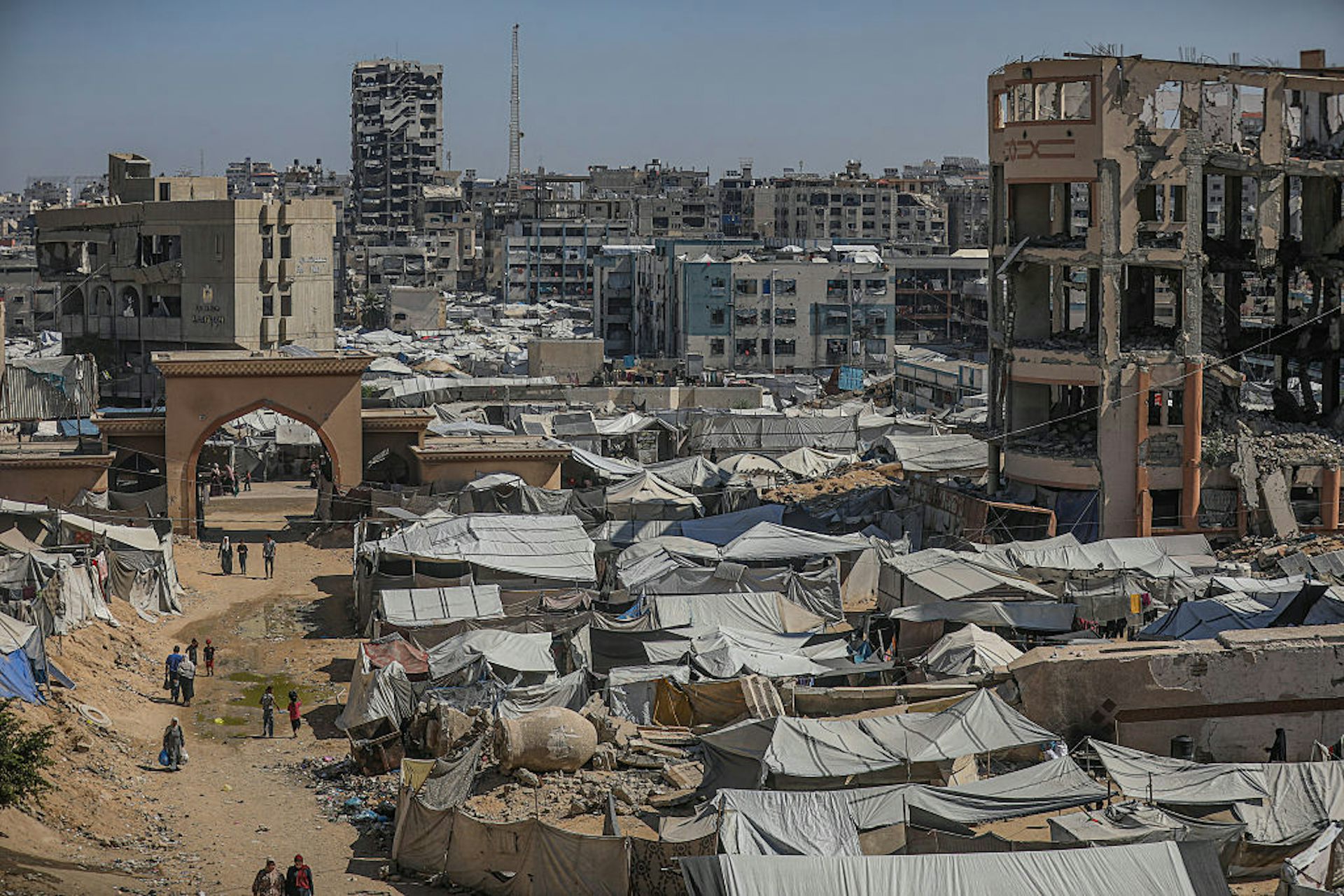 Photograph of cityscape with buildings destroyed by bombs and makeshift tents set up.