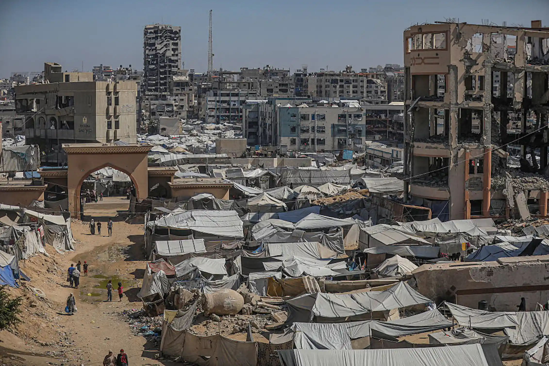 Photograph of cityscape with buildings destroyed by bombs and makeshift tents set up.