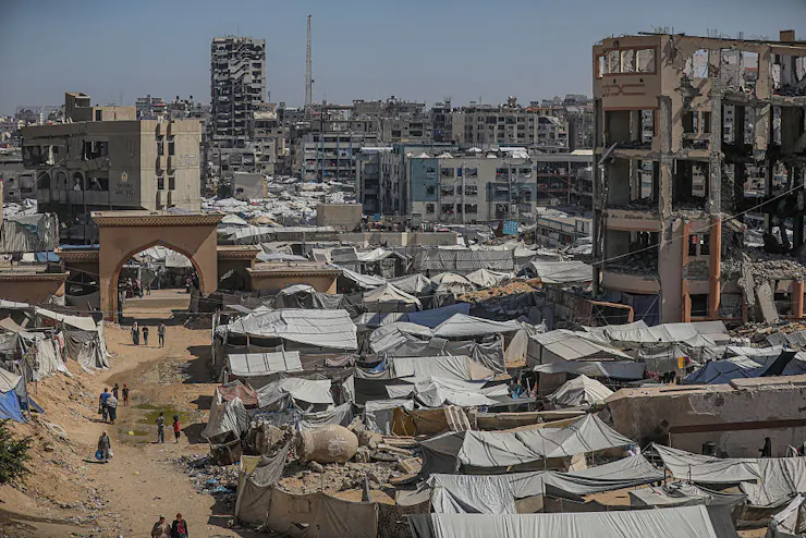 Photograph of cityscape with buildings destroyed by bombs and makeshift tents set up.