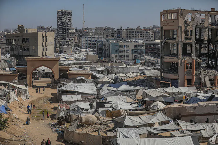 Photograph of cityscape with buildings destroyed by bombs and makeshift tents set up.