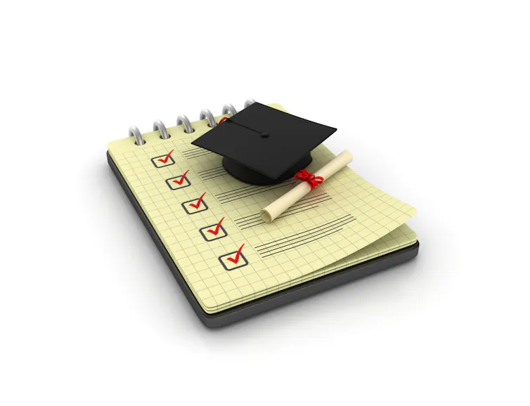 A paper shows lines and a series of checkmarks near a black graduation cap and diploma.