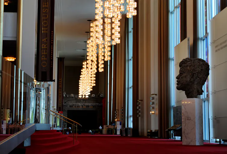 A bust of John F. Kennedy looks out over an expanse of red carpet.
