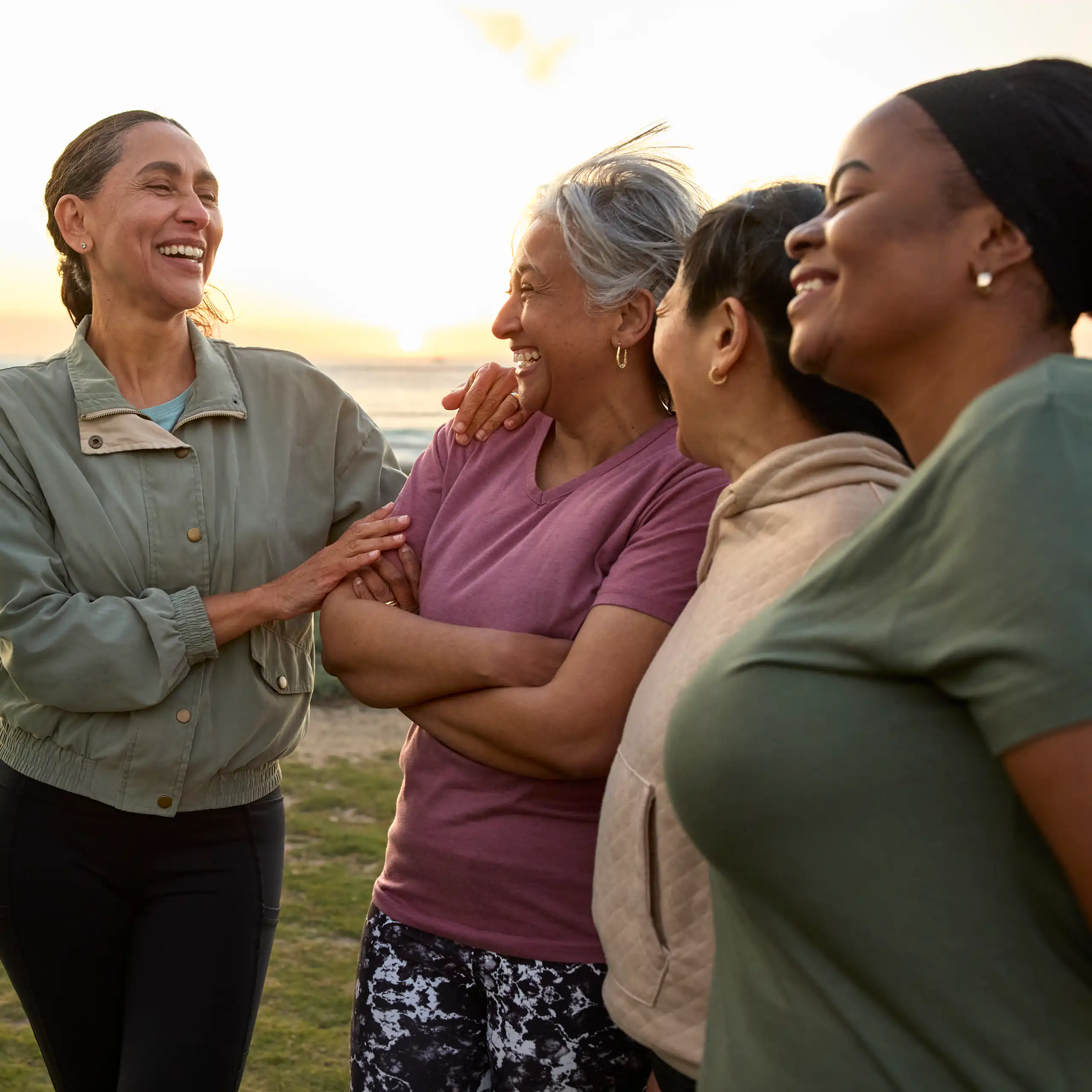 A group of middle-aged women lay and talk on a windy beach