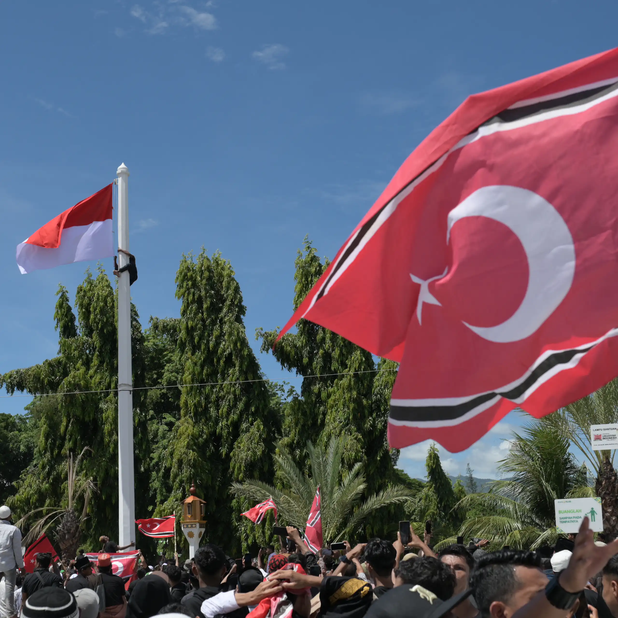 Bendera berlatar merah dengan gambar bulan sabit berkibar tertiup angin.