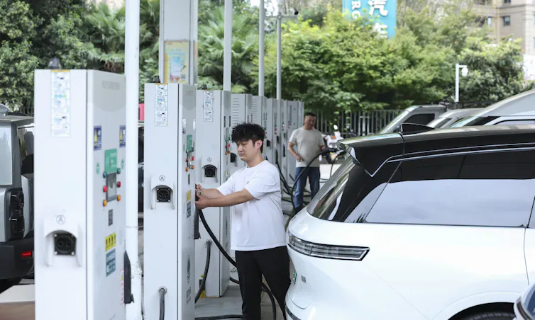 A person plugs a car into a charging station.