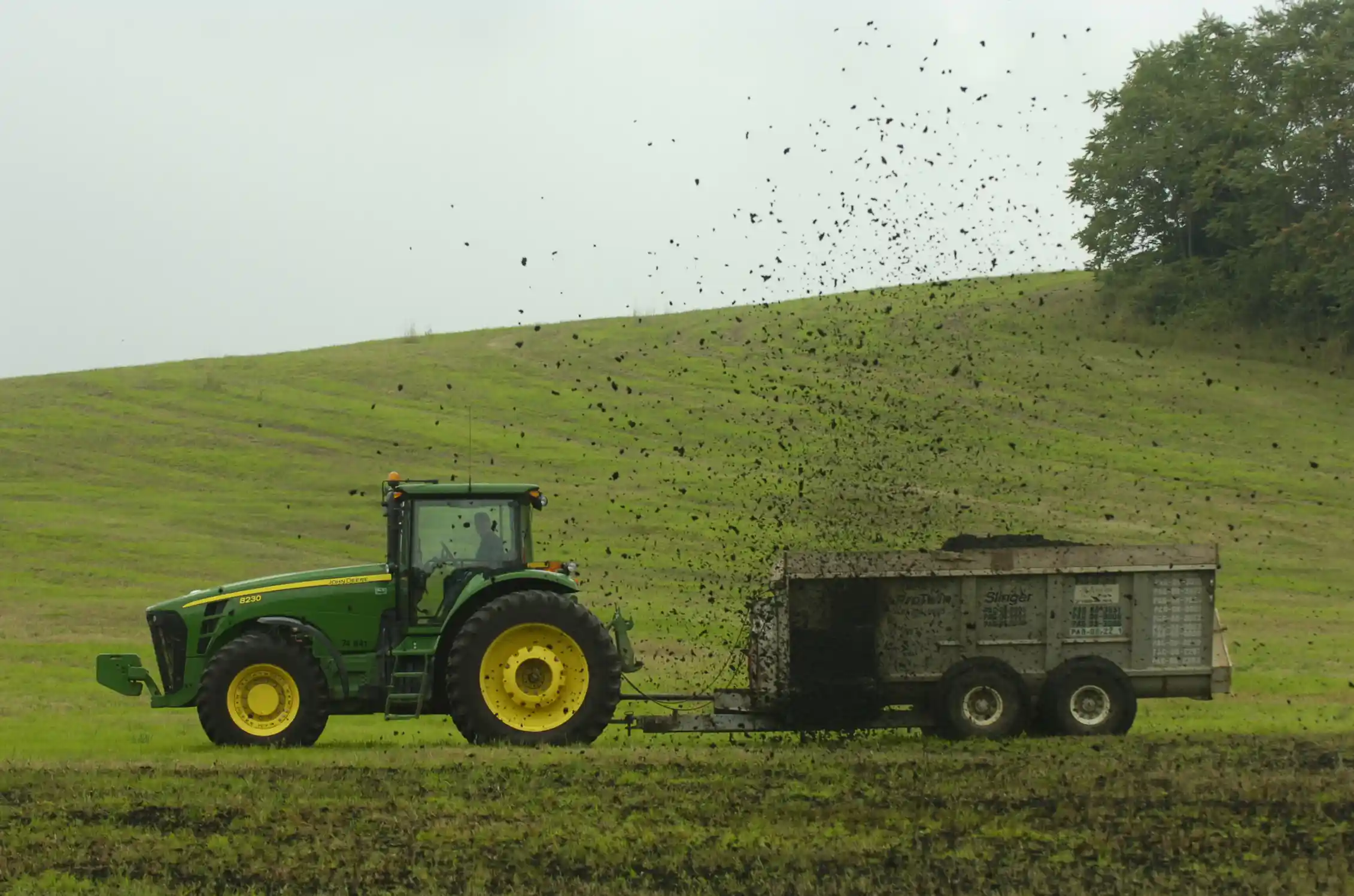 A tractor pulls a trailer across a grassy area.