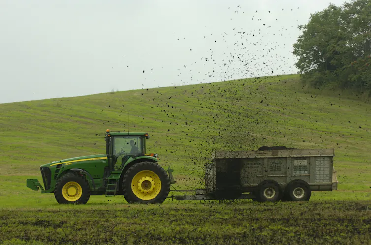 A tractor pulls a trailer across a grassy area.