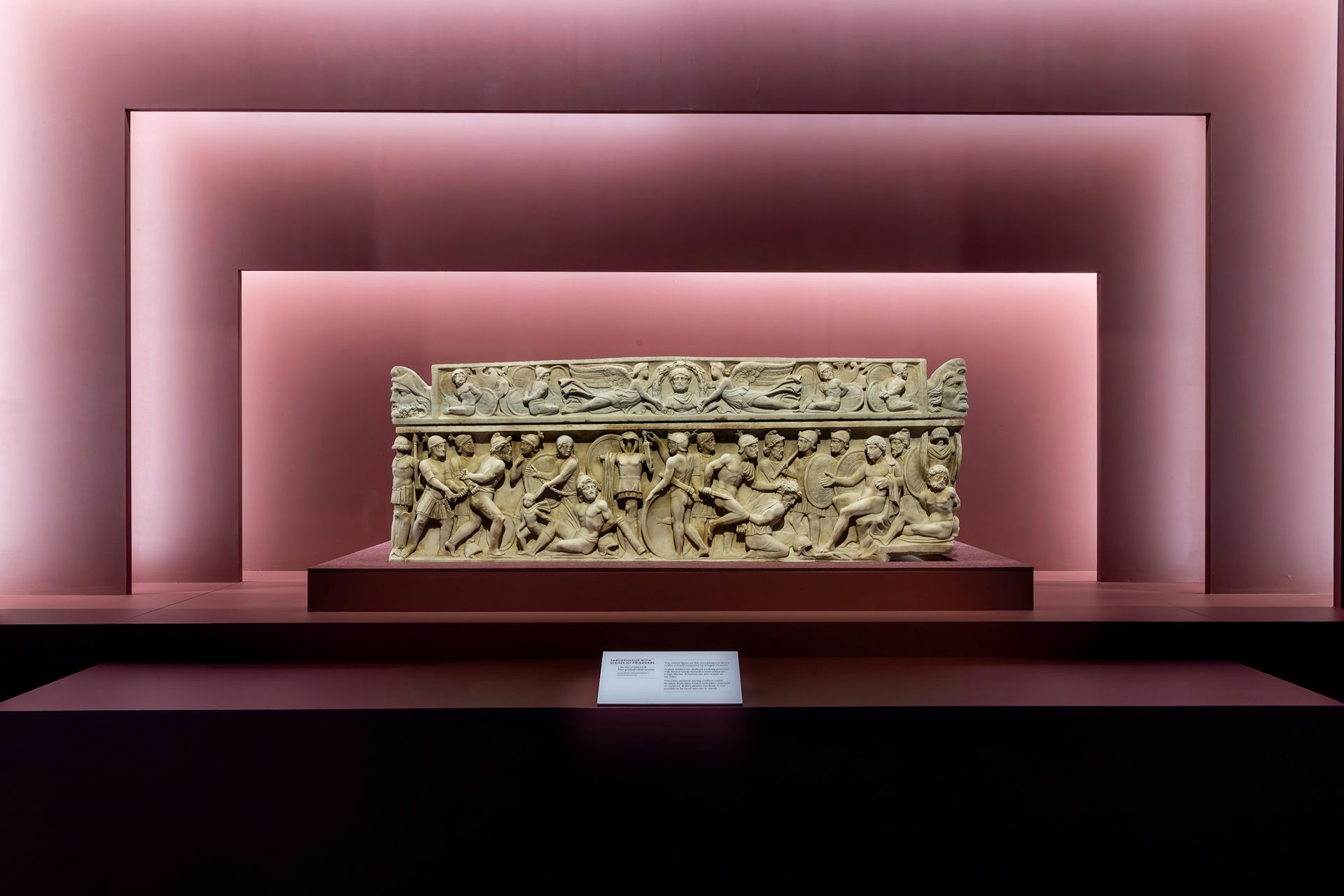 A carved Sarcophagus framed by musk-pink wall architecture.