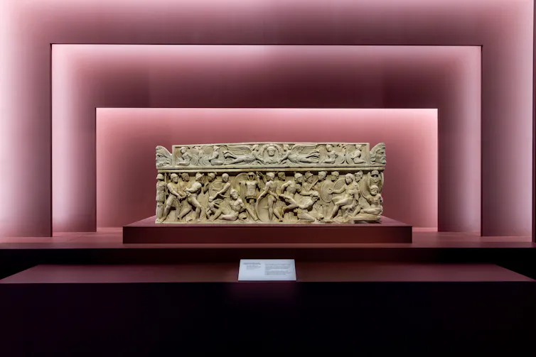A carved Sarcophagus framed by musk-pink wall architecture.