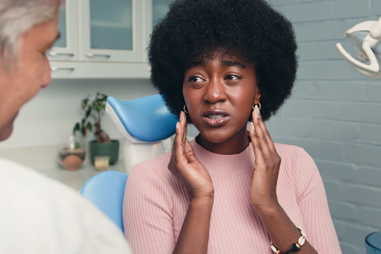 Woman with orthodontic braces holds her hands near her cheeks.