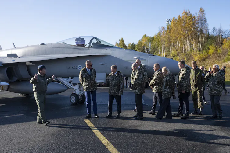 A group of EU leaders stand next to a fighter jet at an airbase in Rovaniemi.