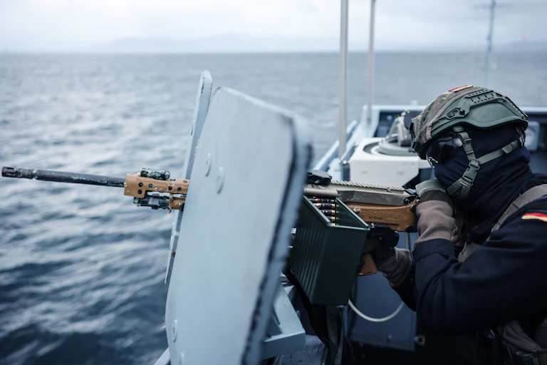 A German soldier points a machine gun out to sea from a boat off the coast of Norway.