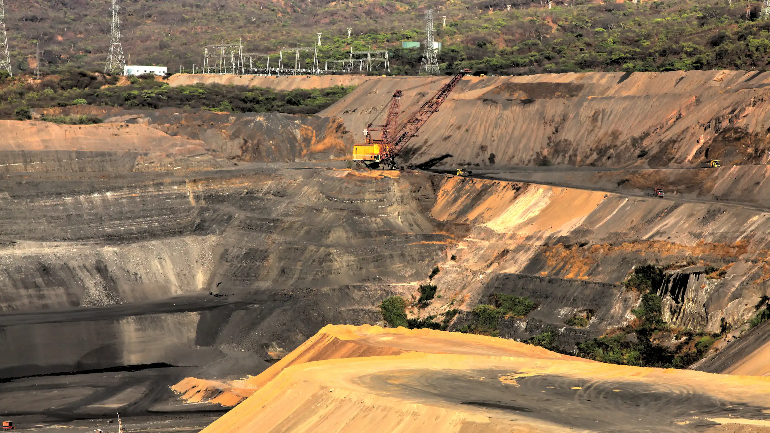 yellow brown layers of open coal pit, trucks and engineering equipment