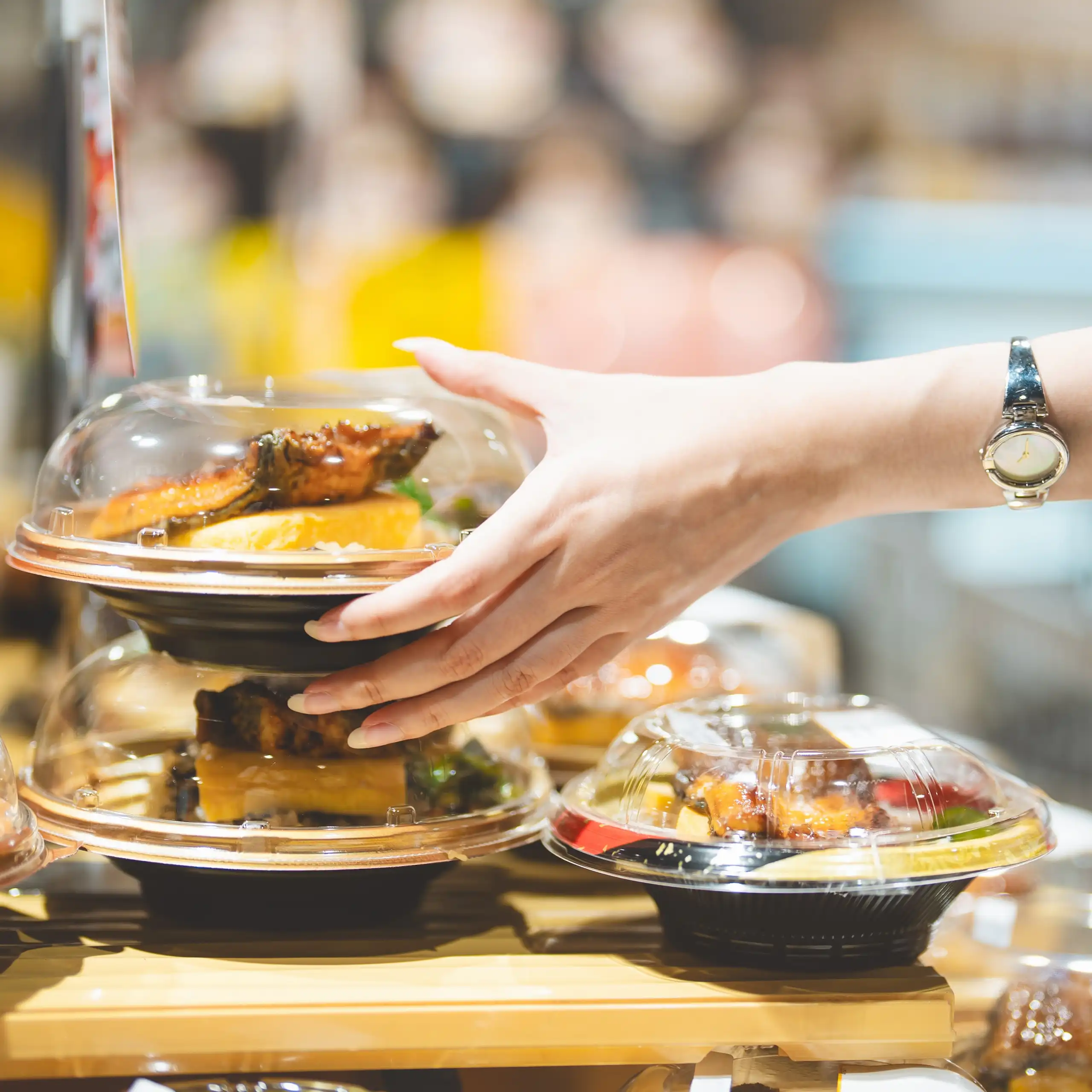 Una persona coge de una repisa un plato preparado en un envase de plástico
