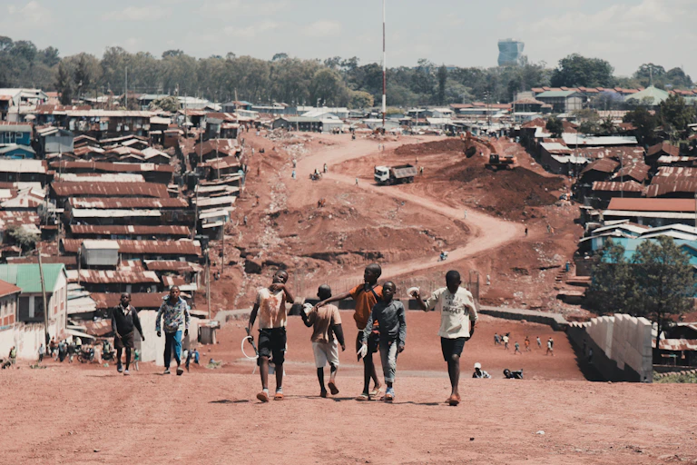 Children walk on an unpaved road in an urban settlement