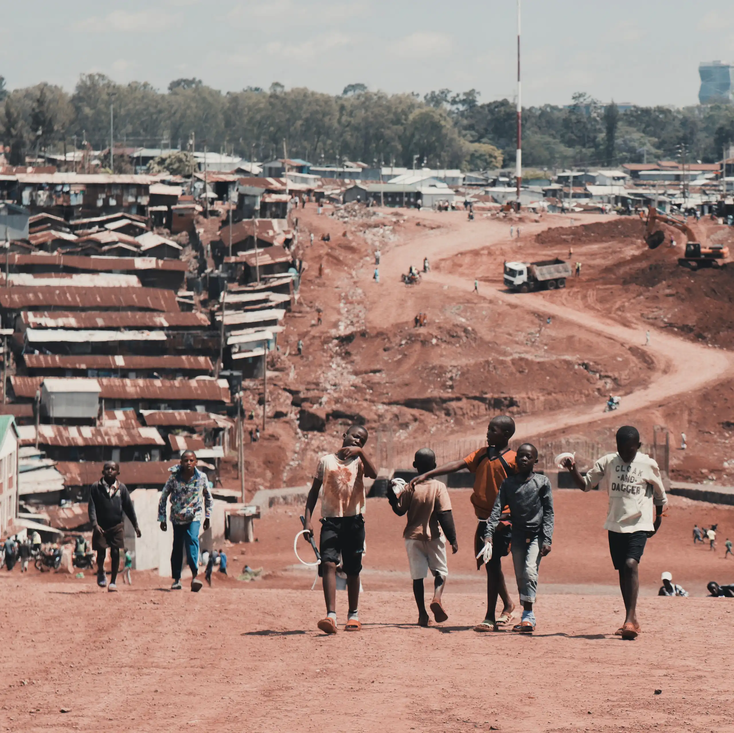 Children walk on an unpaved road in an urban settlement