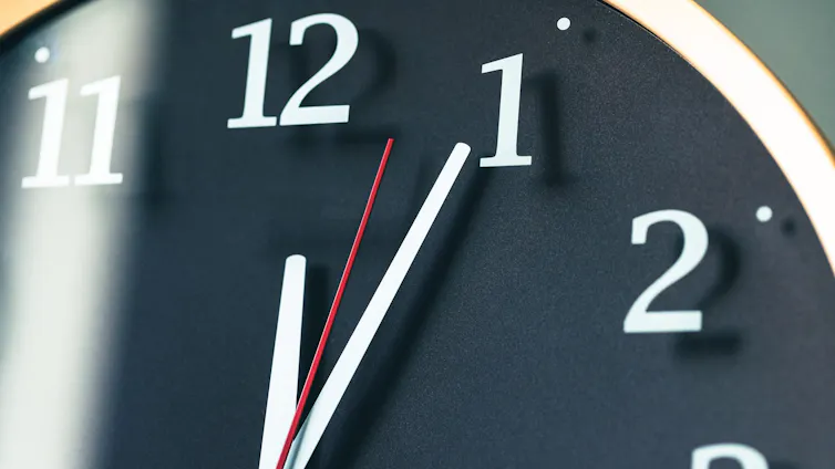 A zoomed-in shot of the upper right corner of a clock, from 12 to 3, with all three hands pointing between 12 and 1