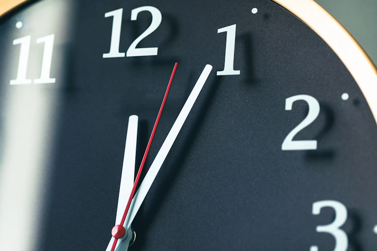 A zoomed-in shot of the upper right corner of a clock, from 12 to 3, with all three hands pointing between 12 and 1