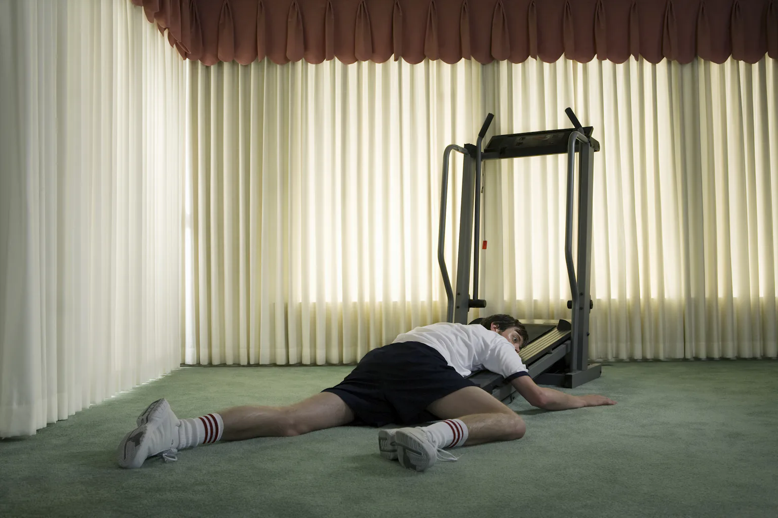 Person lying half on a treadmill, half on the ground