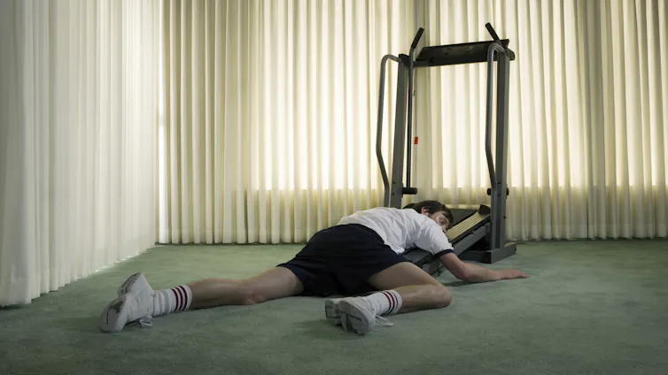 Person lying half on a treadmill, half on the ground